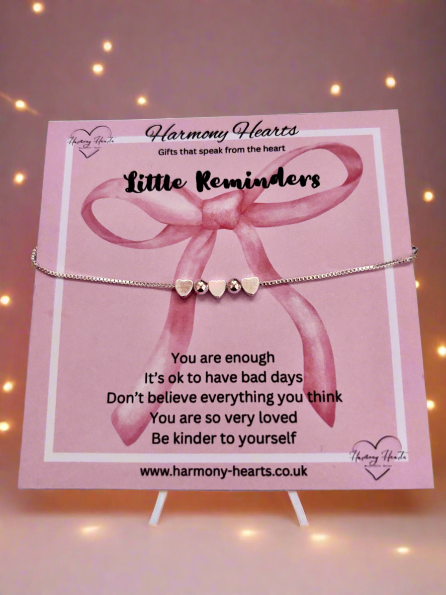Bracelet with pink bow and heart charms on a 'Harmony Hearts' card with motivational message.