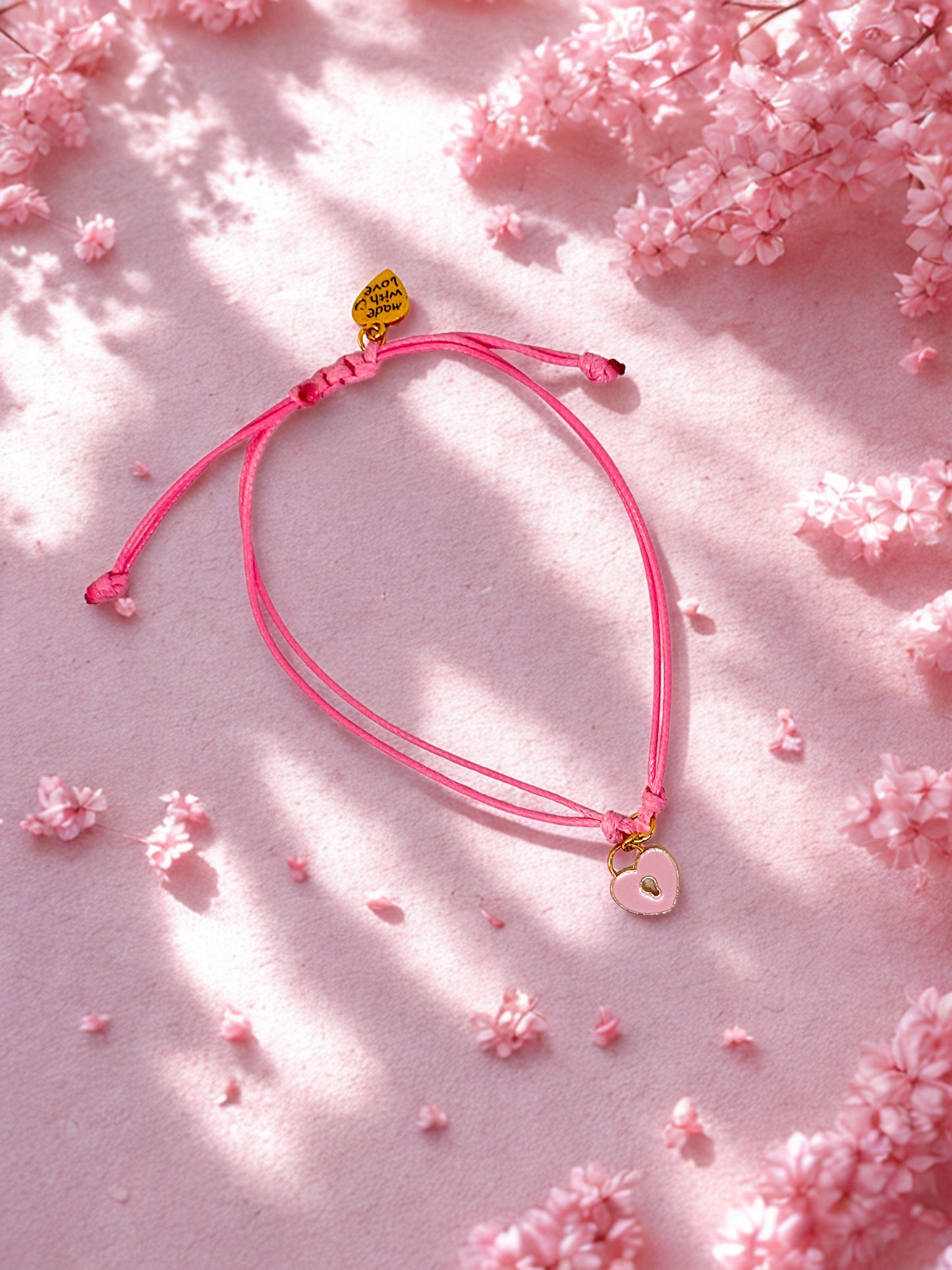 Pink bracelet with heart padlock charm on a pink floral background