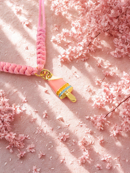 Pink braided cord with a gold lolly charm on a pink floral background