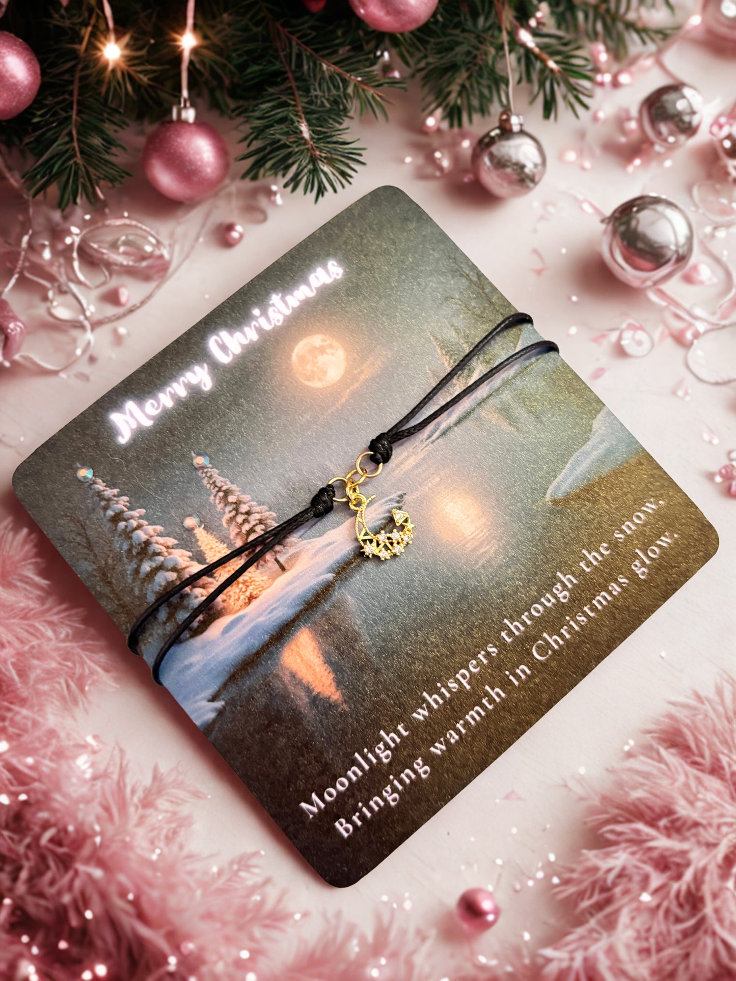 Christmas-themed card with a gold moon charm bracelet and decorative elements on a pink background