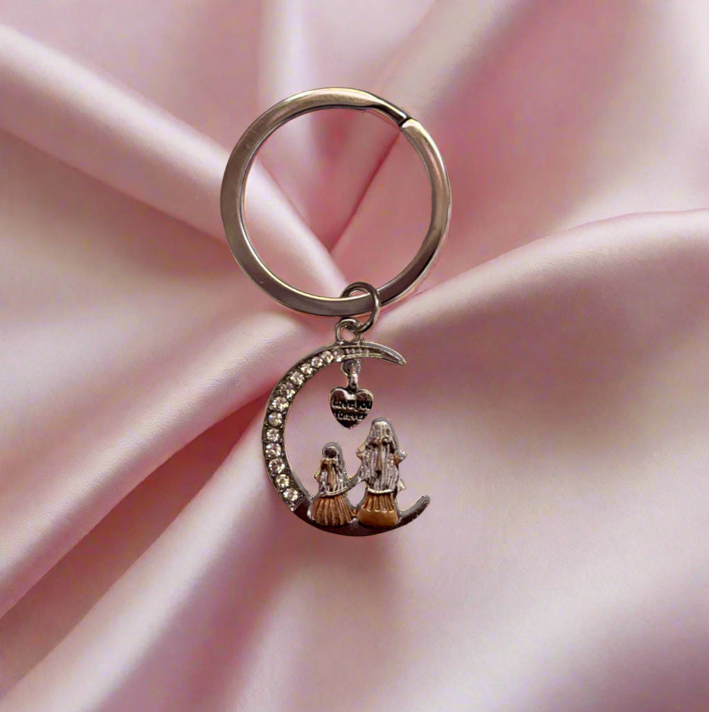 Keychain with a crescent moon design on a pink fabric background