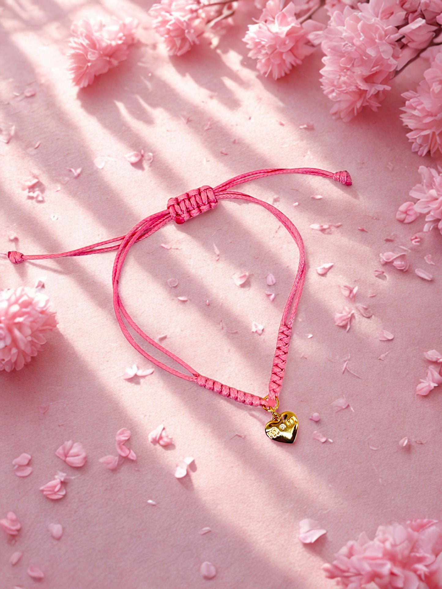 Pink bracelet with a heart-shaped charm on a pink floral background
