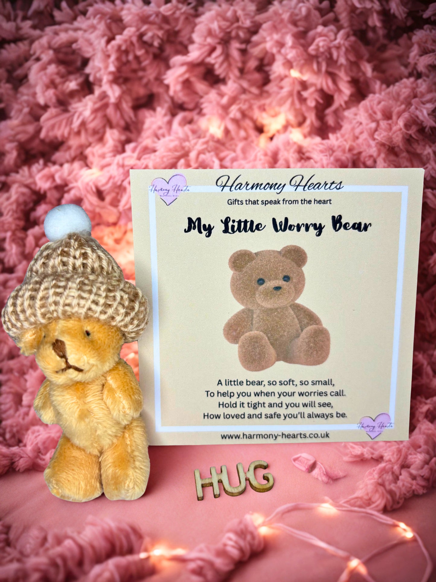 Teddy bear with a hat next to a card on a pink textured background