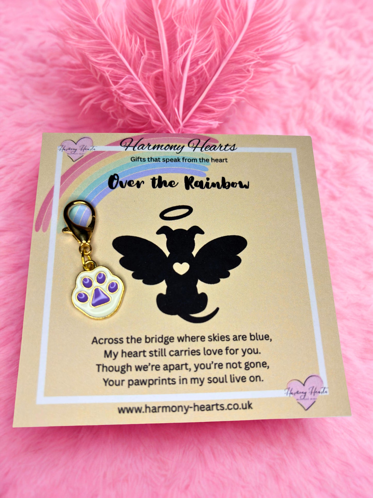 Dog angel charm with purple paw print on a 'Harmony Hearts' card against a pink background