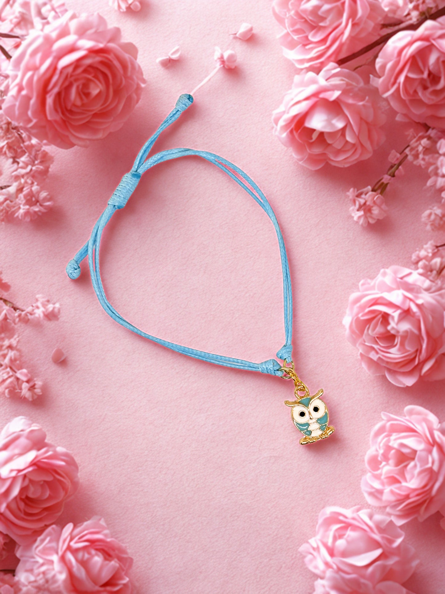 Blue bracelet with an owl charm on a pink floral background