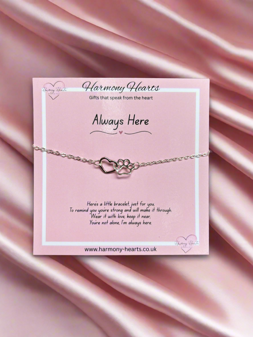 Silver bracelet with heart design on a pink card with 'Harmony Hearts' branding, against a pink satin background.
