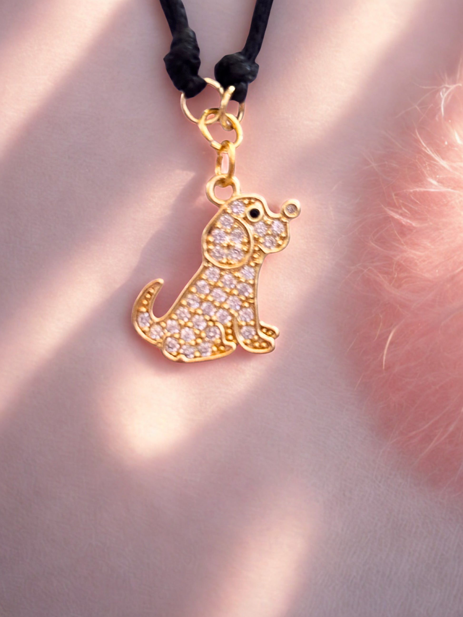 Gold sparkly dog-shaped charm on a pink background