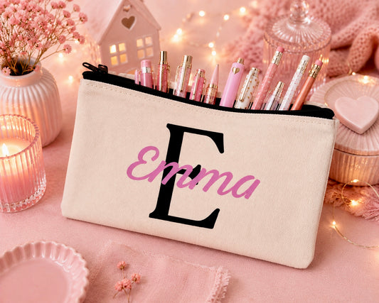 Canvas pencil case with an initial E in black and the name Emma n pink. Pens and pencils displayed coming out the top