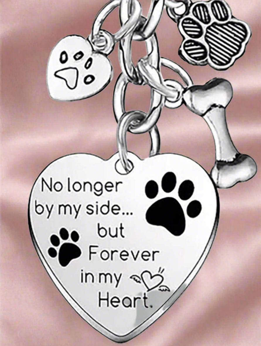 Heart-shaped pendant with paw prints and engraved text on a pink background