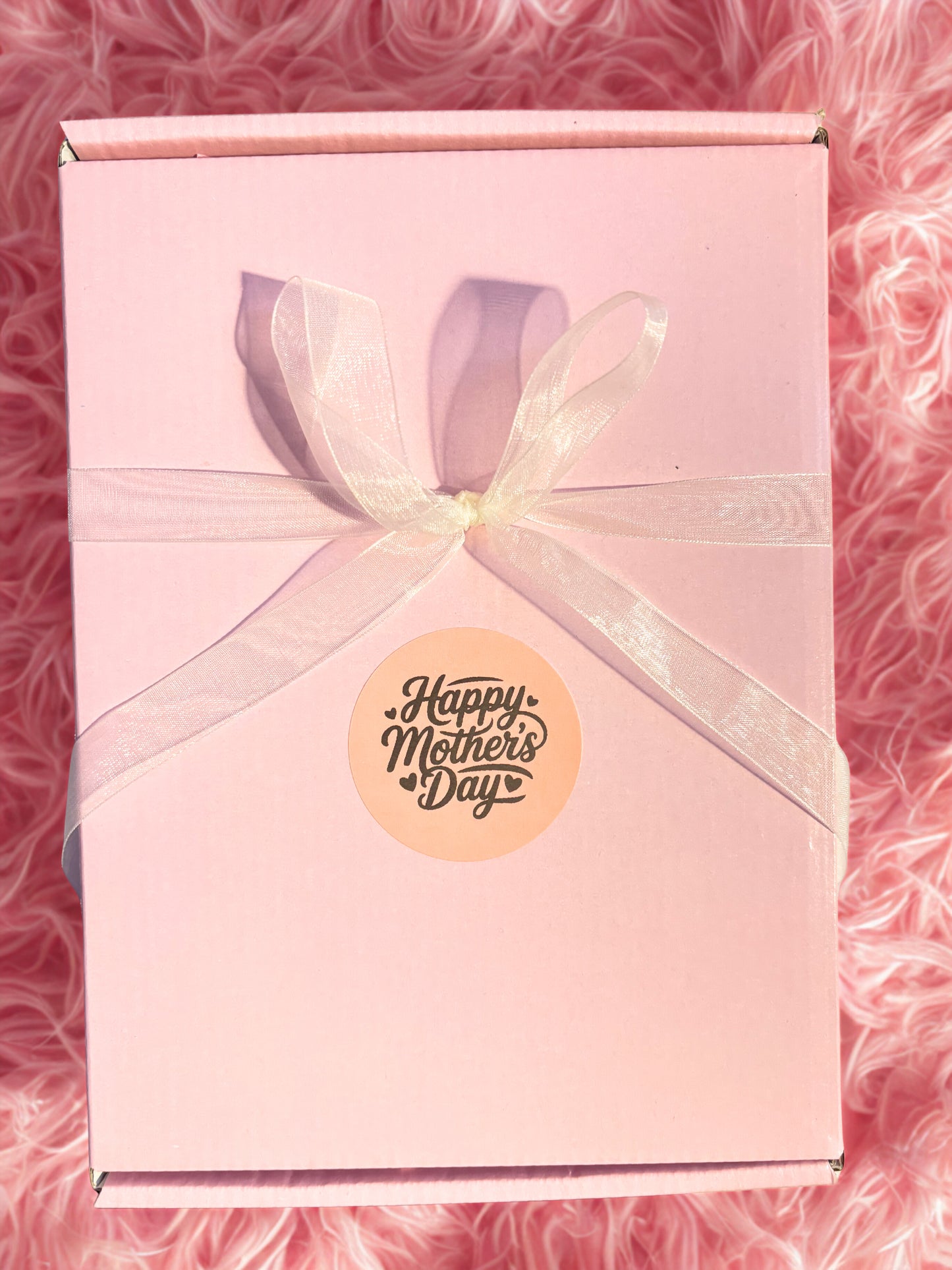 Pink gift box with a 'Happy Mother's Day' sticker on a pink textured background