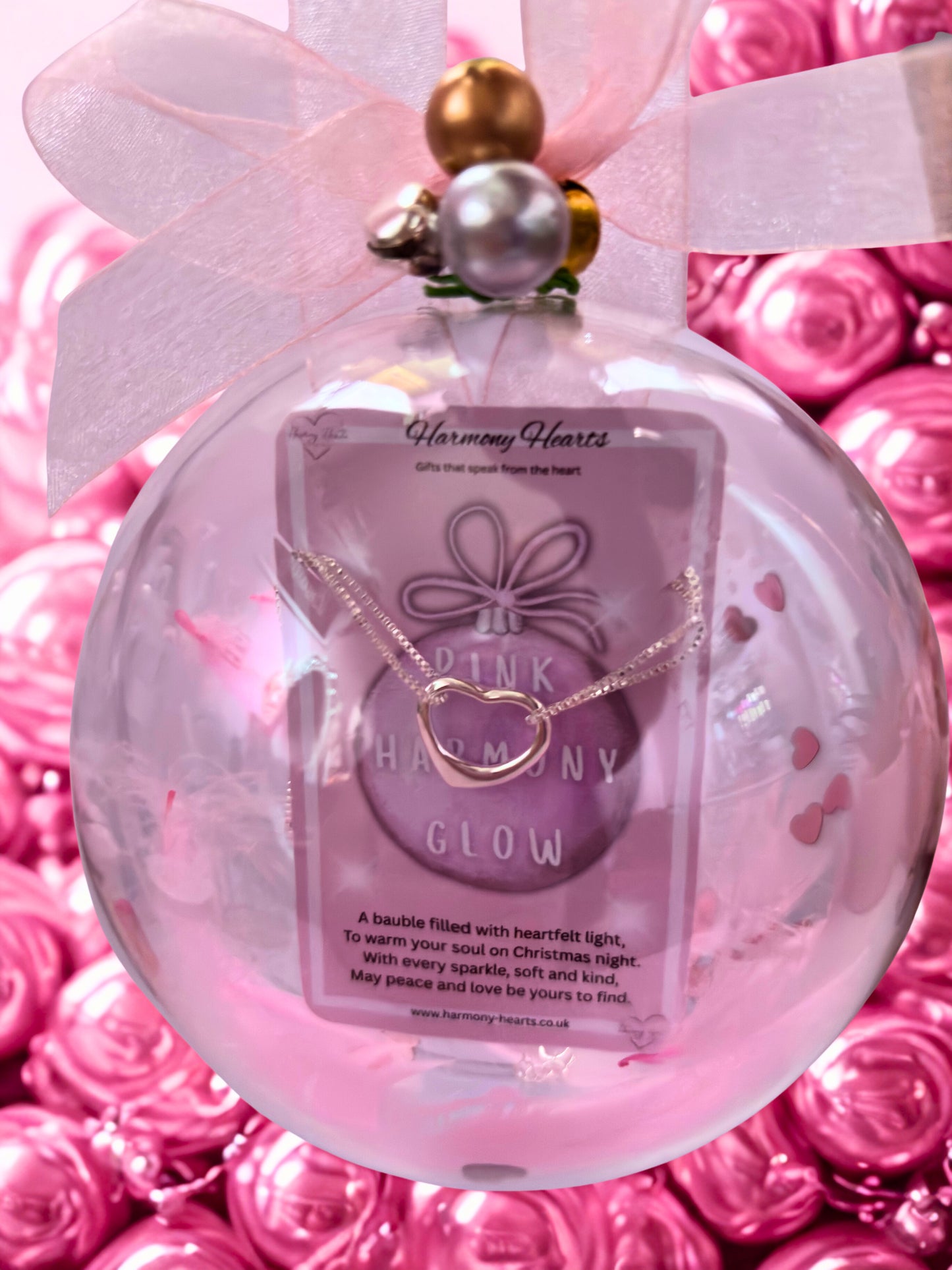 Decorative ornament with a bracelet and packaging labeled 'Pink Harmony Glow' on a pink floral background.
