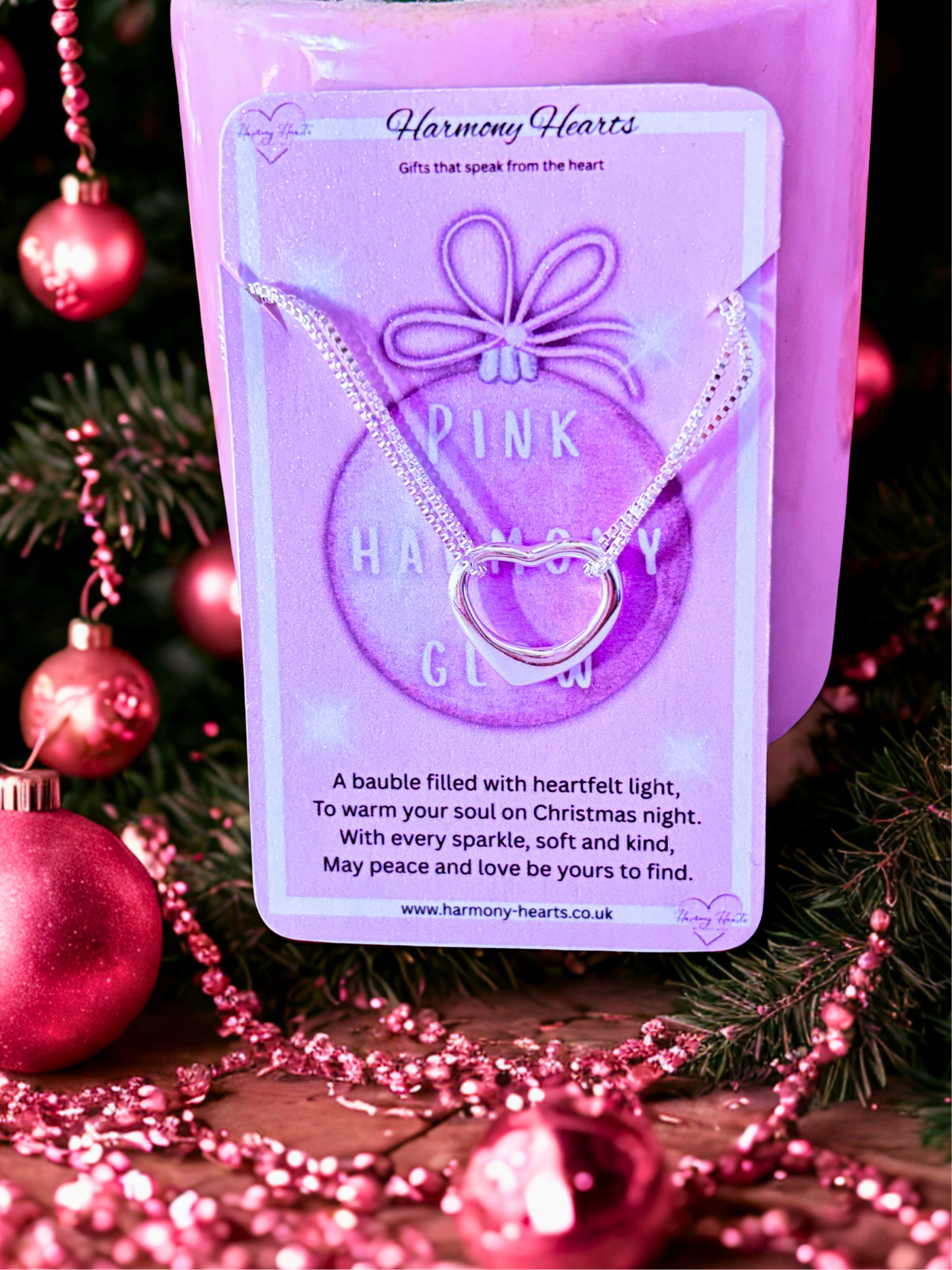 Pink 'Harmony Hearts' bracelet packaging with Christmas decorations in the background