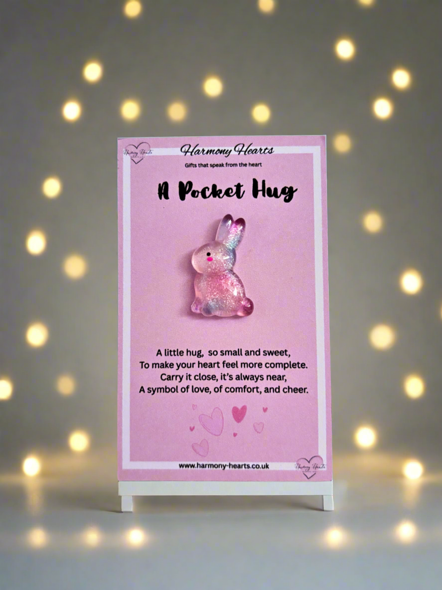 Pink bunny-shaped 'Pocket Hug' charm on a stand with a decorative background