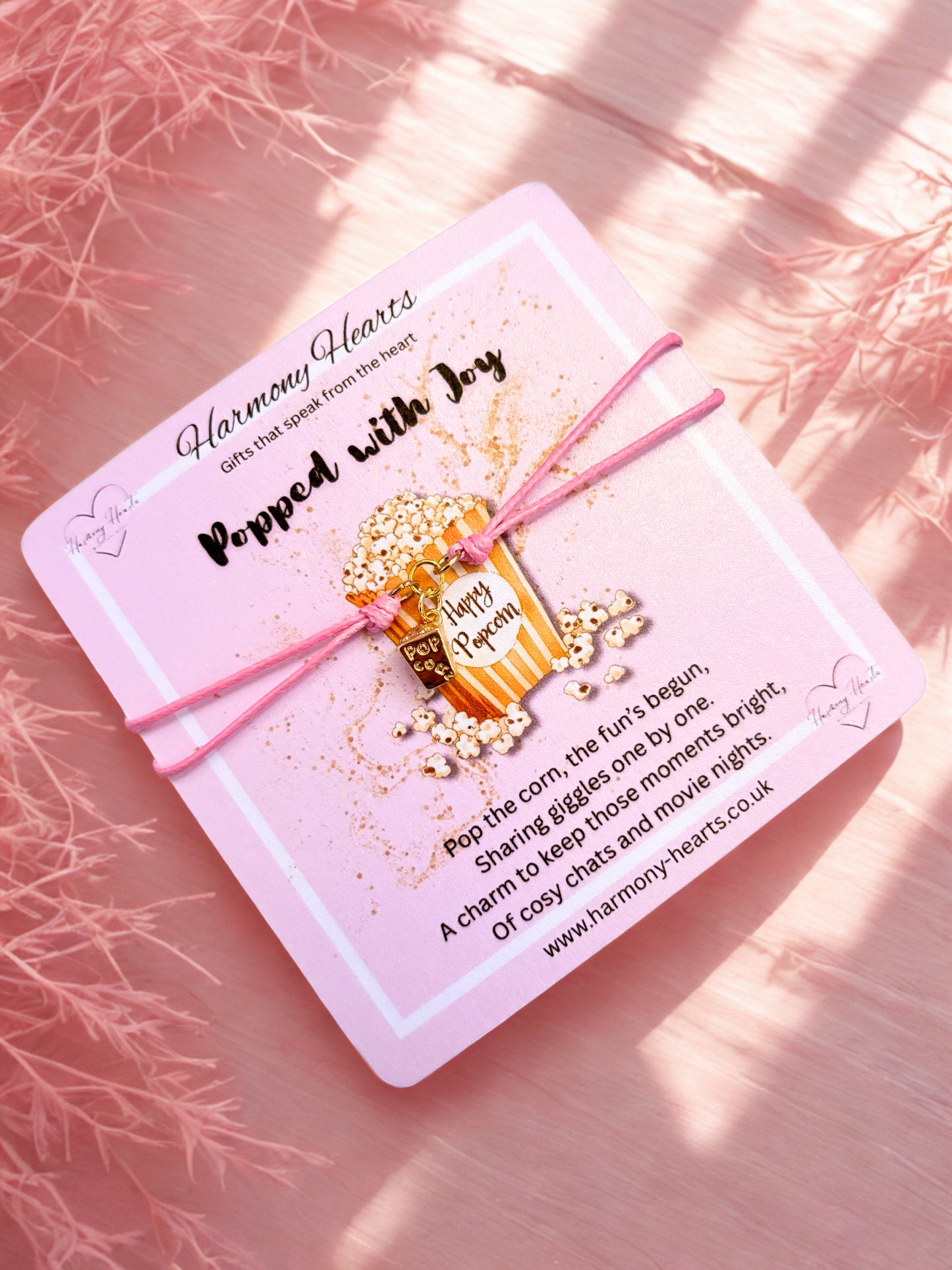 Pink bracelet with popcorn charm on a poem card on a soft pink background
