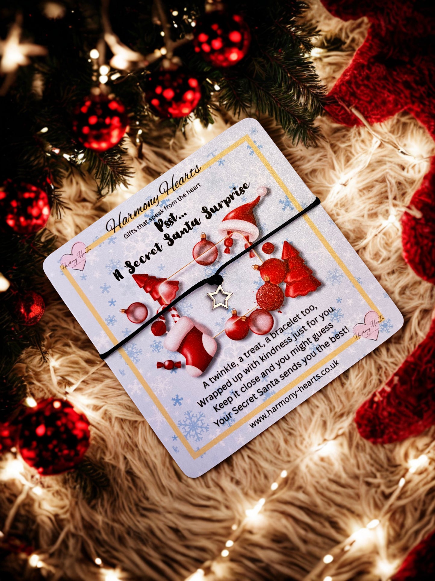 Santa-themed card with star charm bracelet with a Christmas tree and decorations in the background.