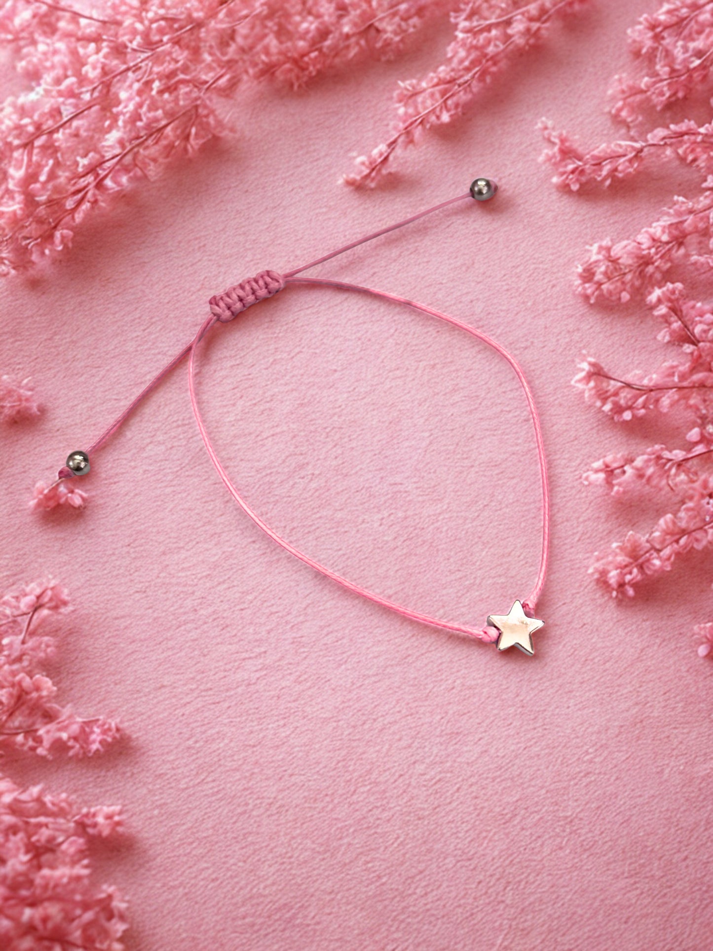 Pink bracelet with star charm on a pink floral background