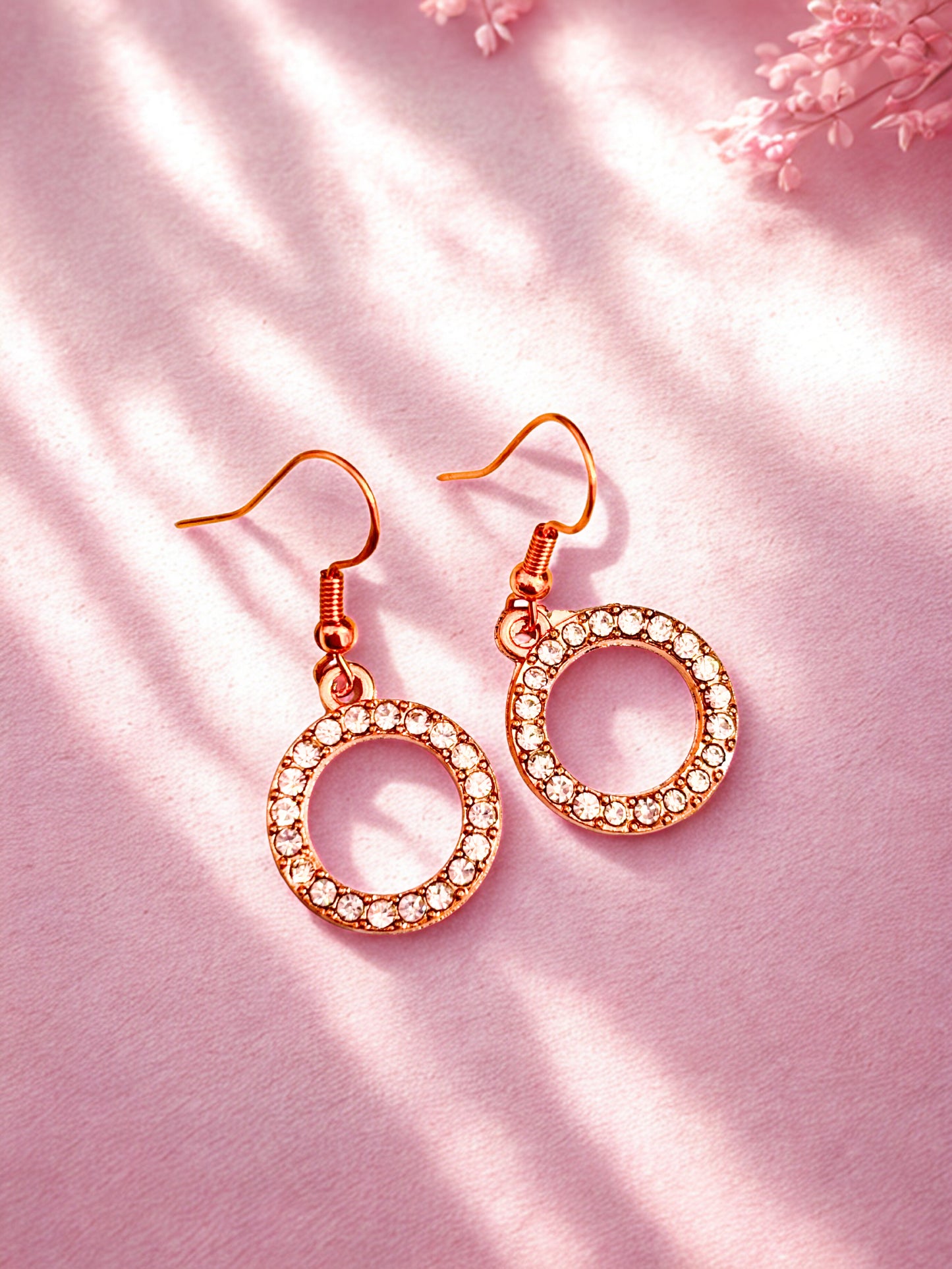 Gold round sparkly earrings on a pink background