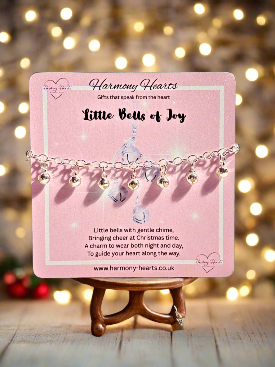 Bracelet with bell charms on a pink card with 'Harmony Hearts' branding, against a festive background.