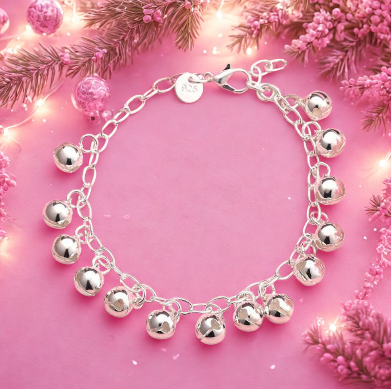 Silver bracelet with bell charms on a pink background with floral decorations