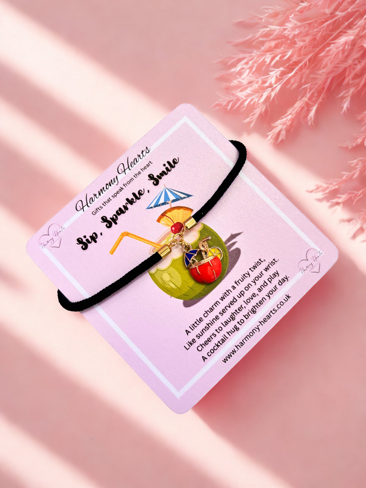 Black charm bracelet with a green apple charm on a pink card with text