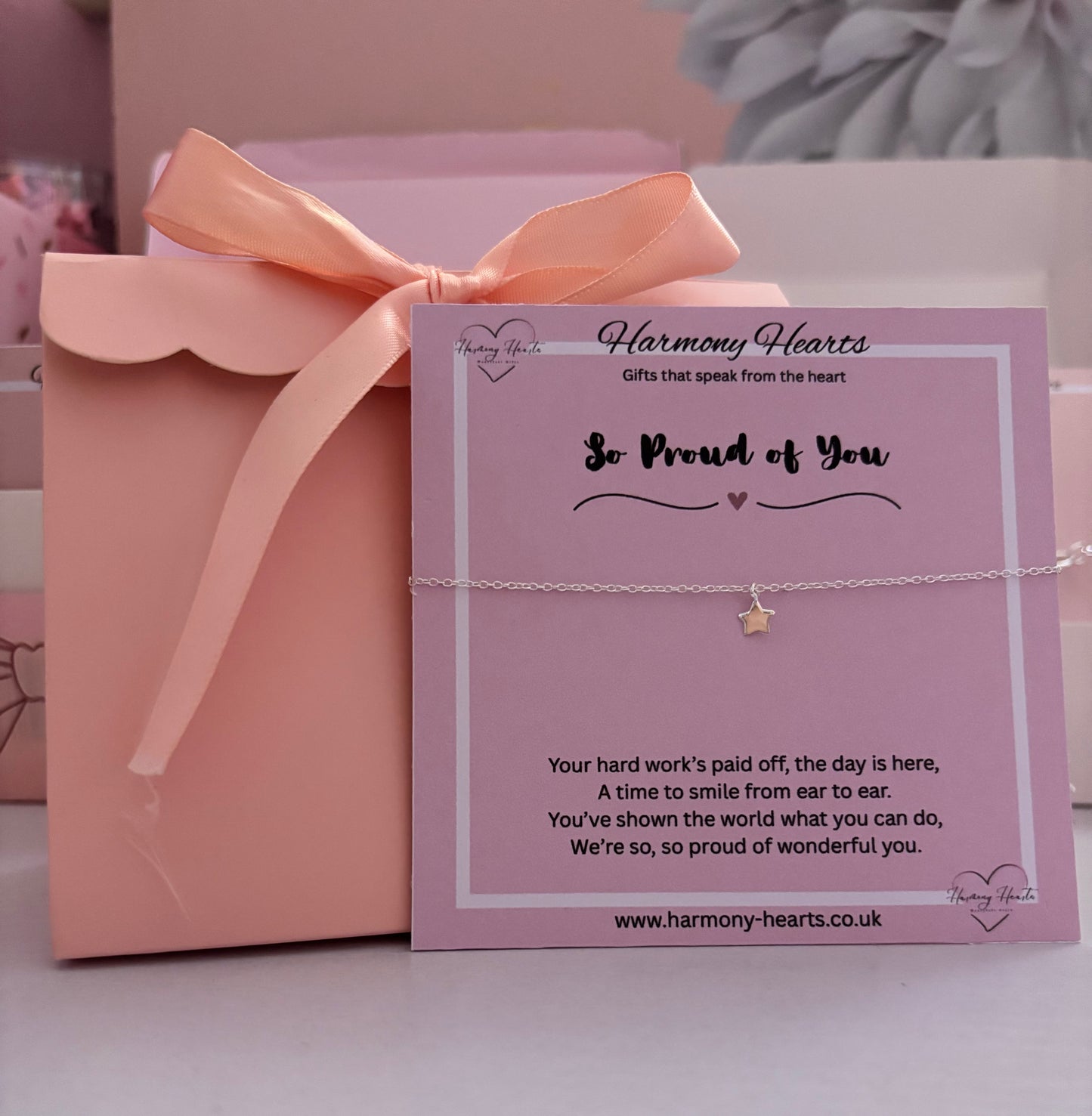 Gift box with a pink ribbon and a card from Harmony Hearts on a light background