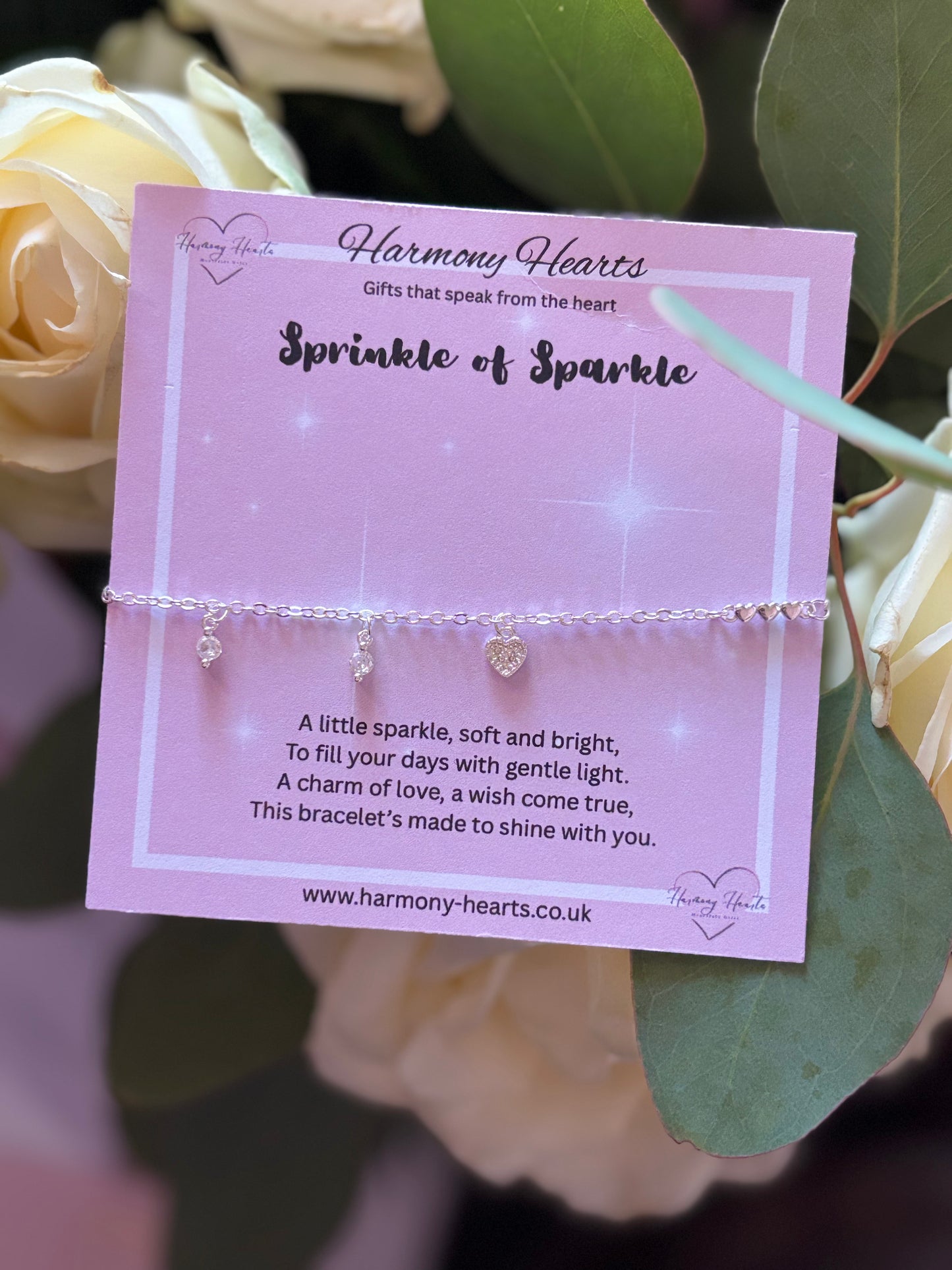 Bracelet on a pink card with 'Harmony Hearts' branding, surrounded by flowers.