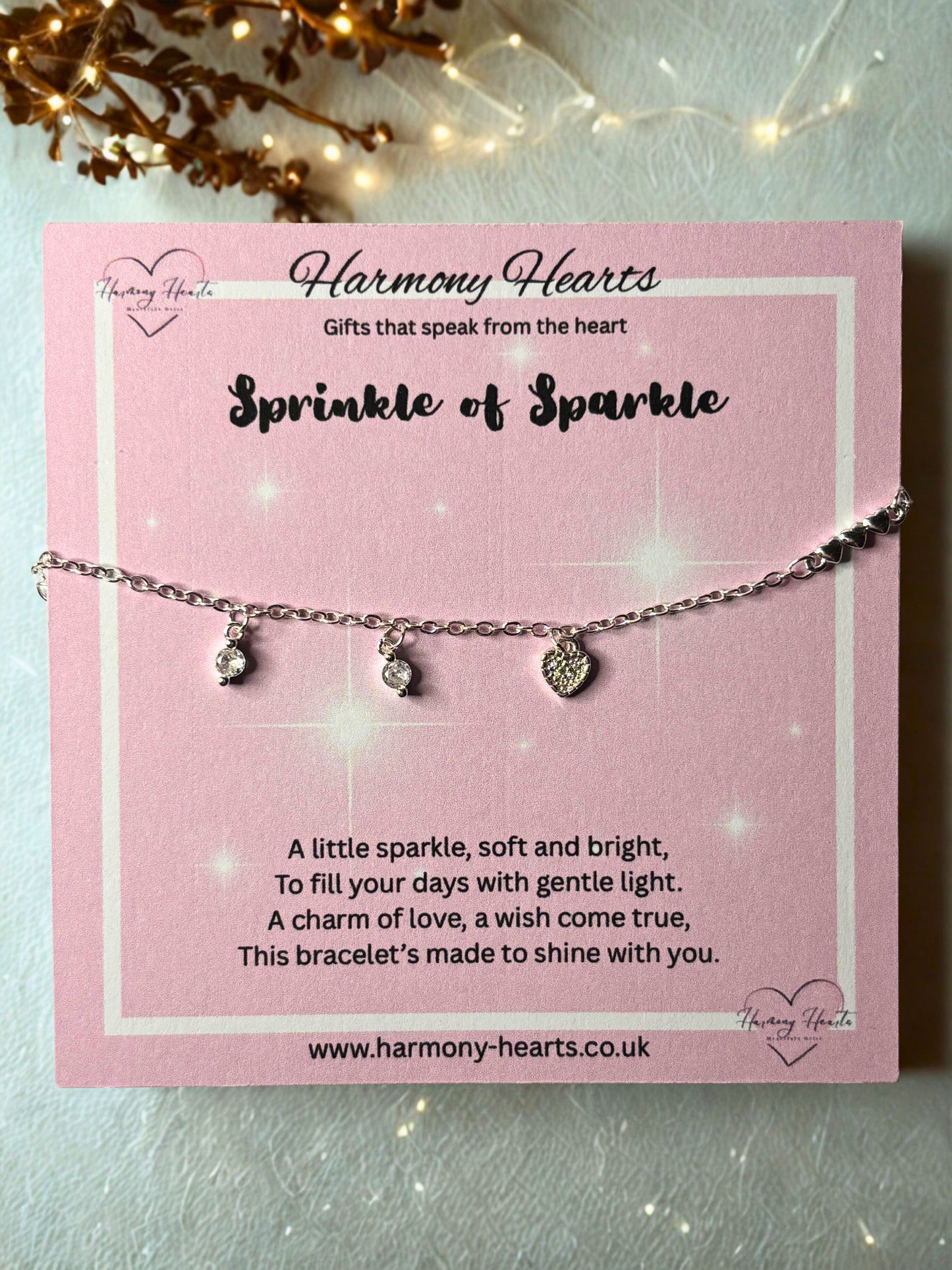 Silver bracelet with charms on a pink card from Harmony Hearts