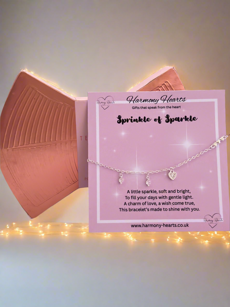 Bracelet with heart charm on a pink card with 'Harmony Hearts' branding, set against a soft light background.