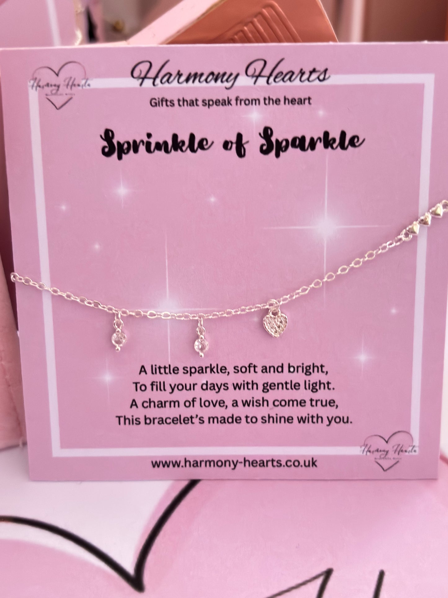 Silver tone bracelet with heart charm on a pink card with 'Harmony Hearts' branding
