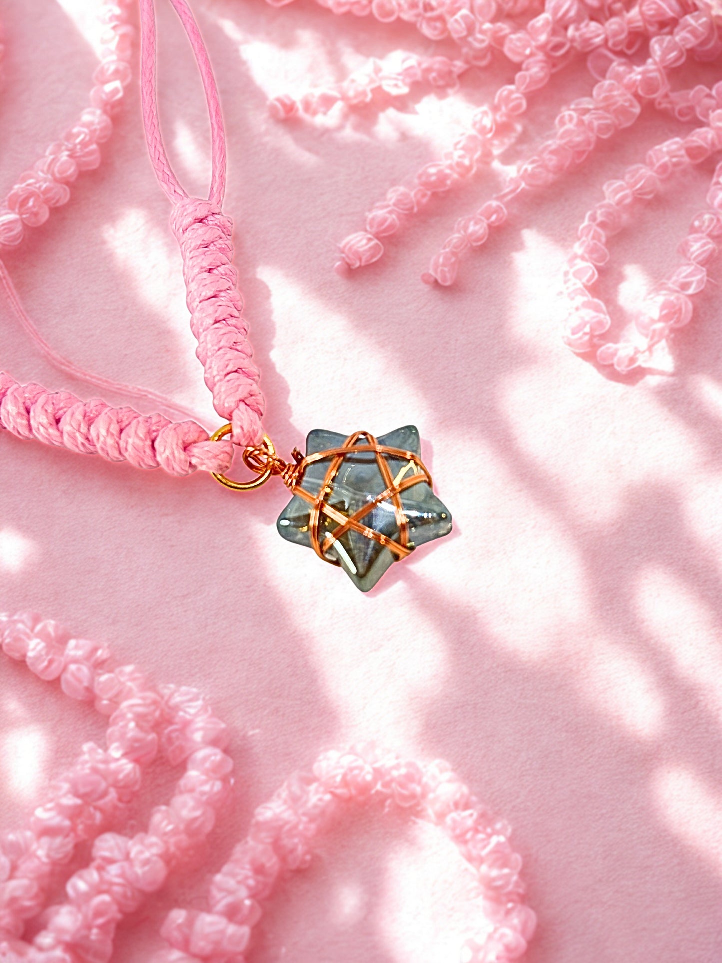 Pink bracelet with a star-shaped charm on a pink textured background