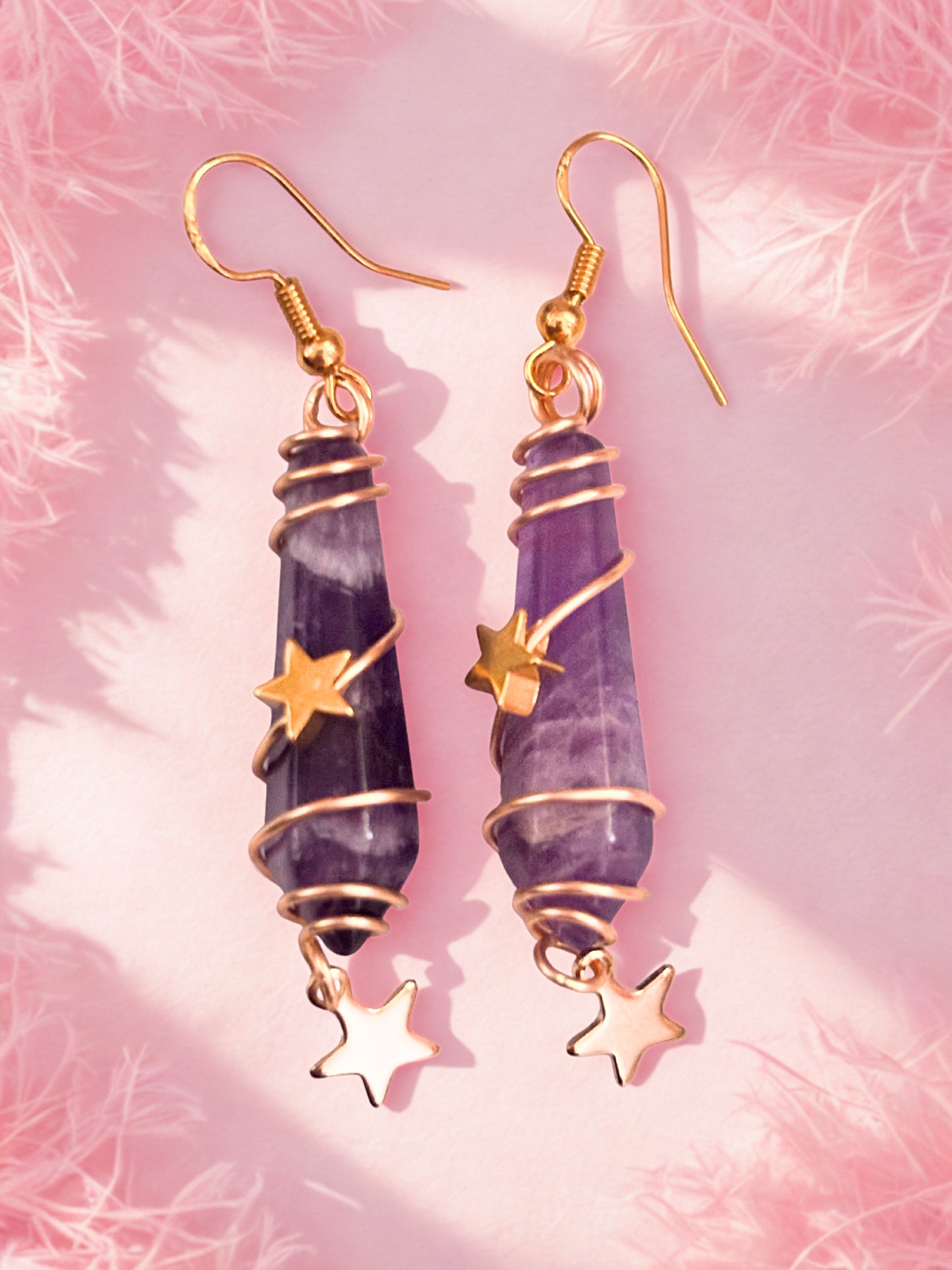 Purple amethyst earrings with gold accents on a pink textured background