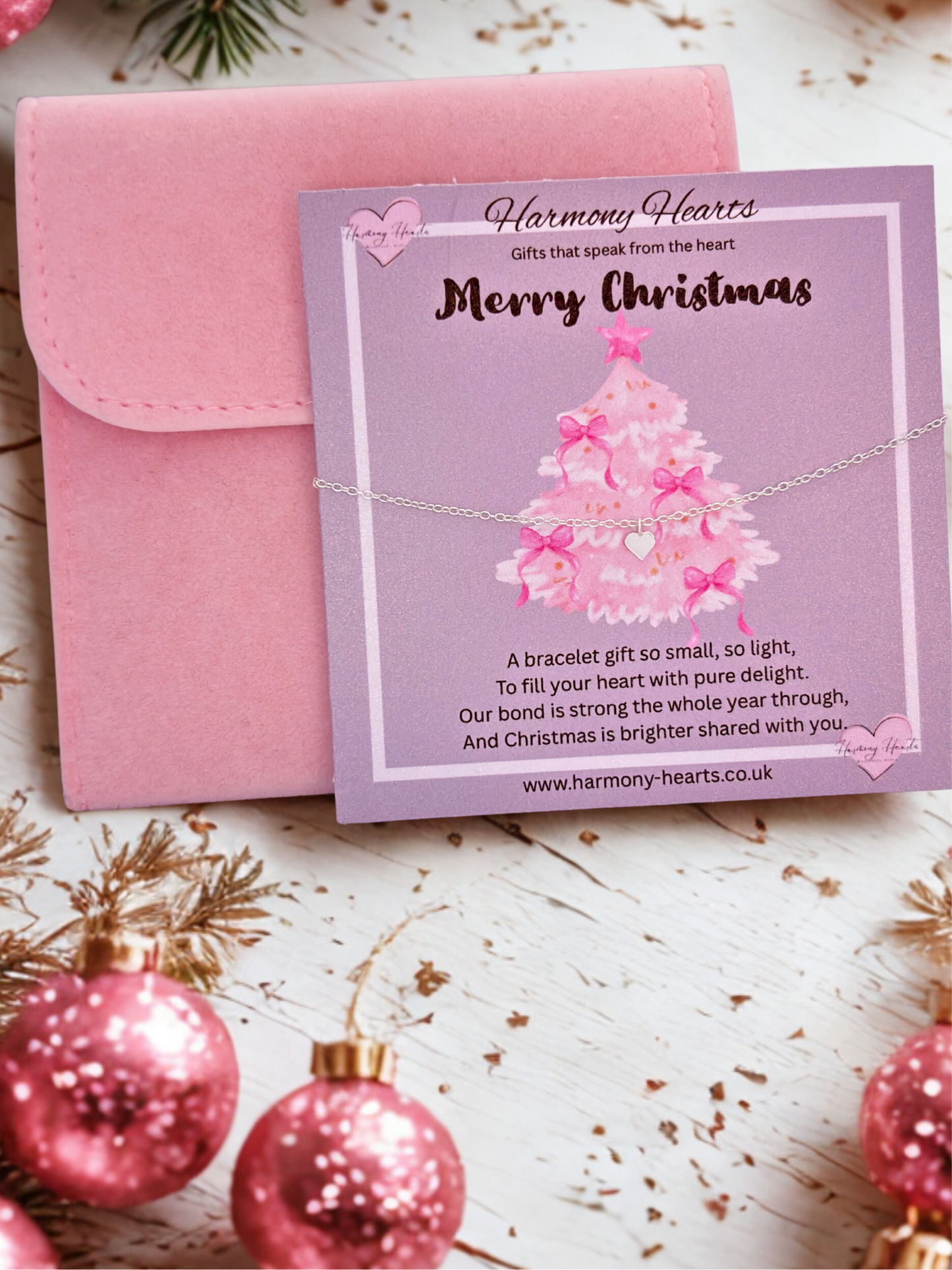 Pink bracelet with a Christmas tree design on a card, surrounded by pink ornaments.
