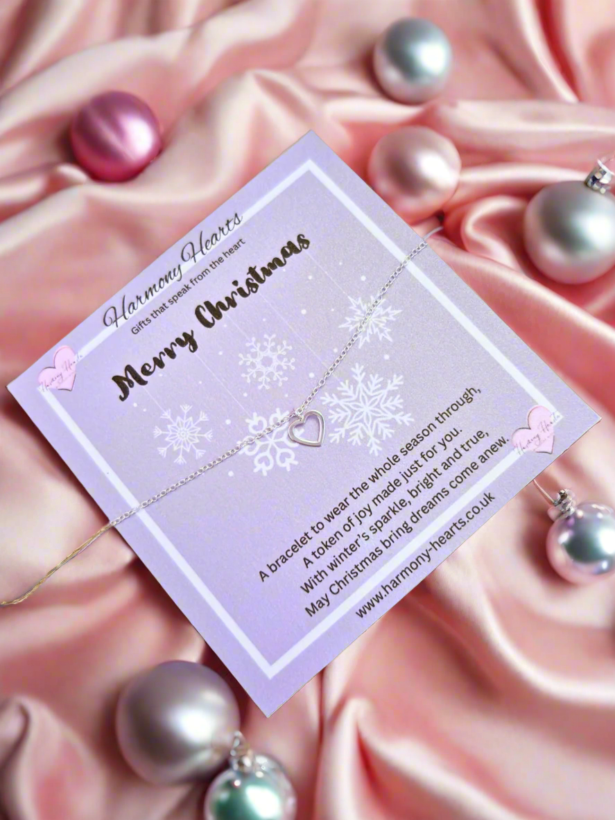Bracelet with a heart and snowflake design on a purple card with text, surrounded by pink satin and pearls.