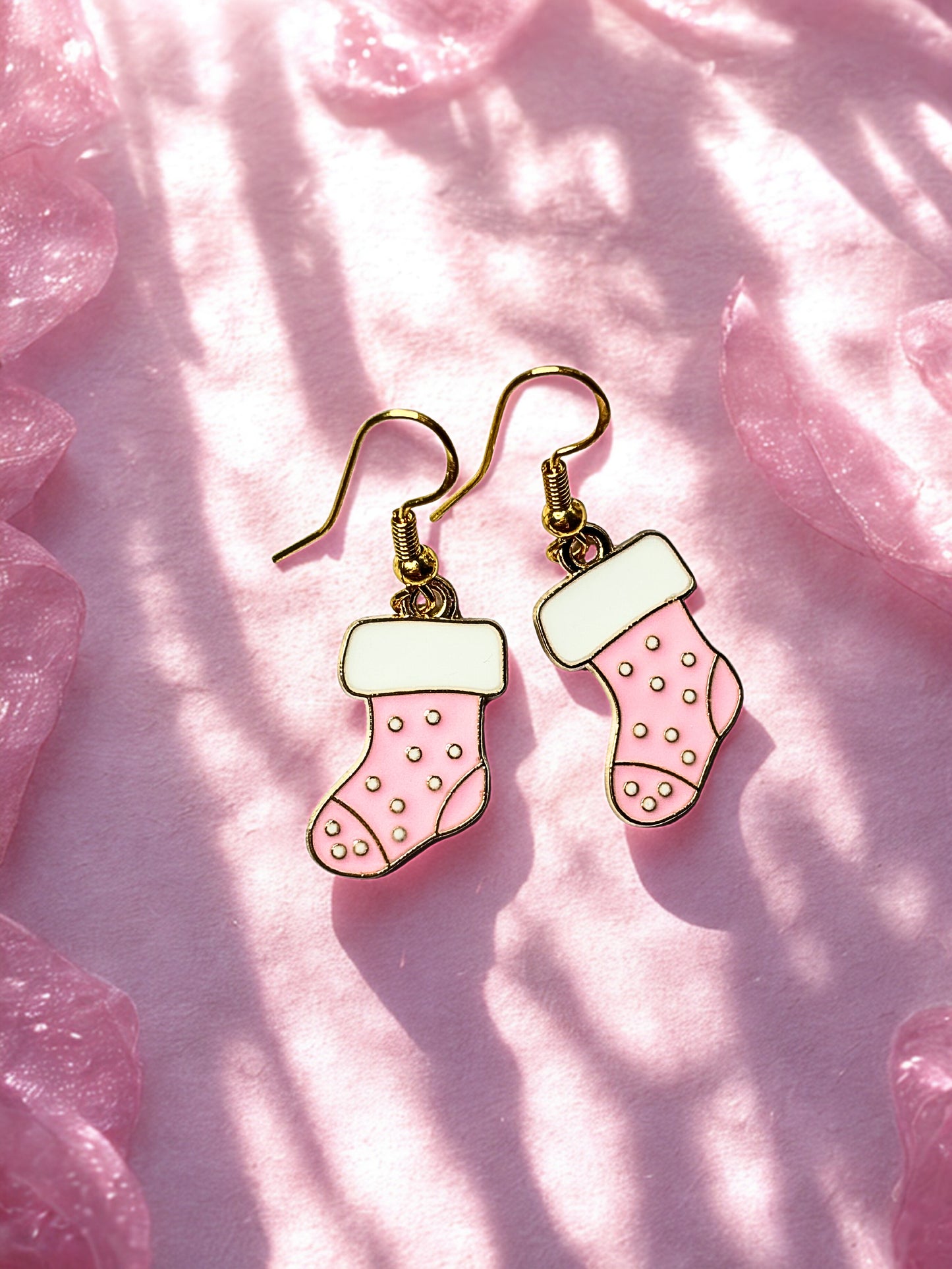 Pink stocking-shaped earrings on a pink textured background