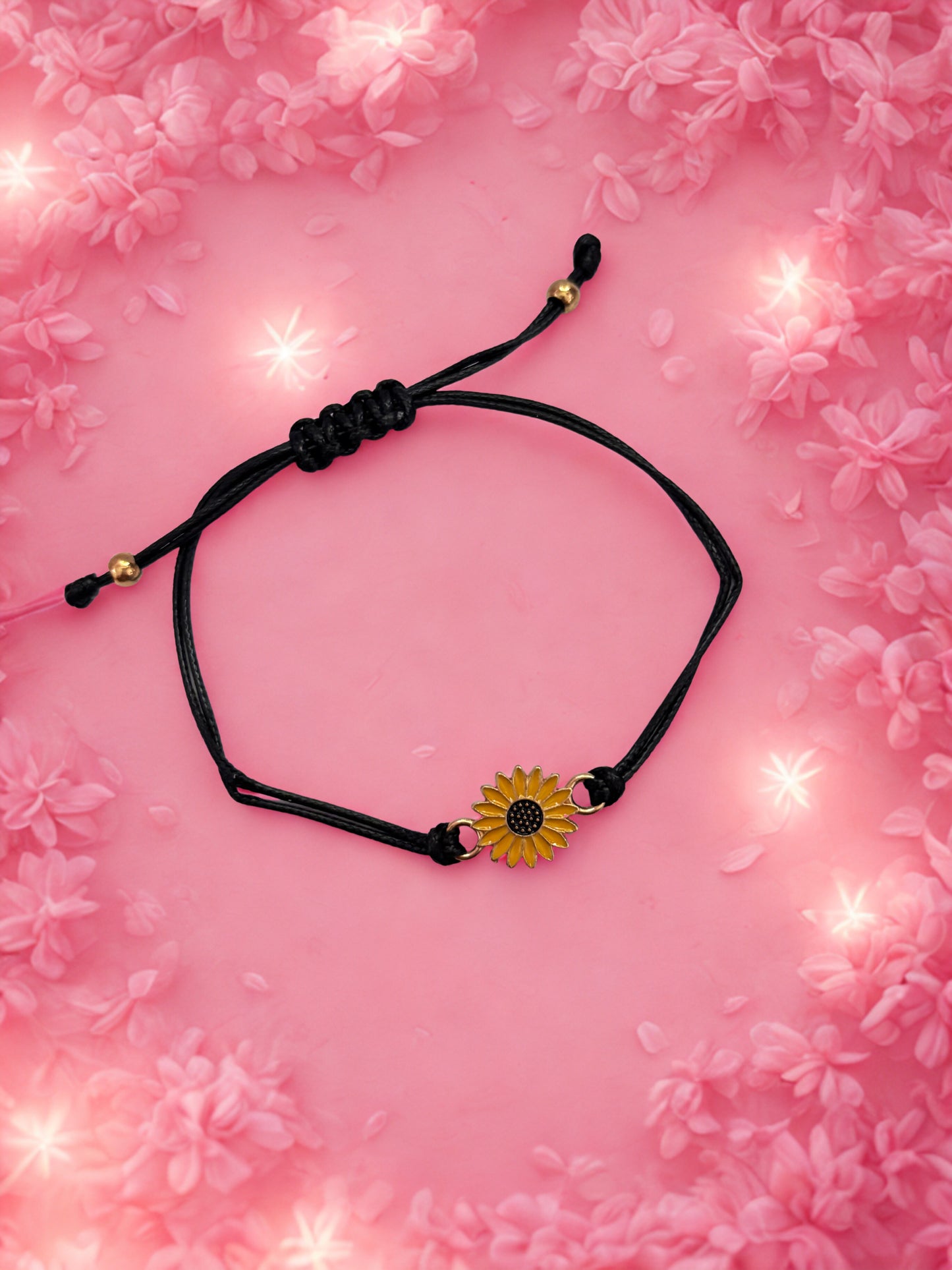 Black cord bracelet with a sunflower charm on a pink floral background