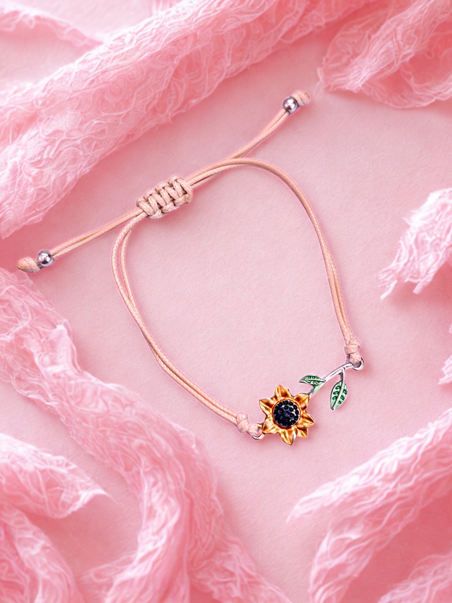 Bracelet with sunflower charm on a pink fabric background