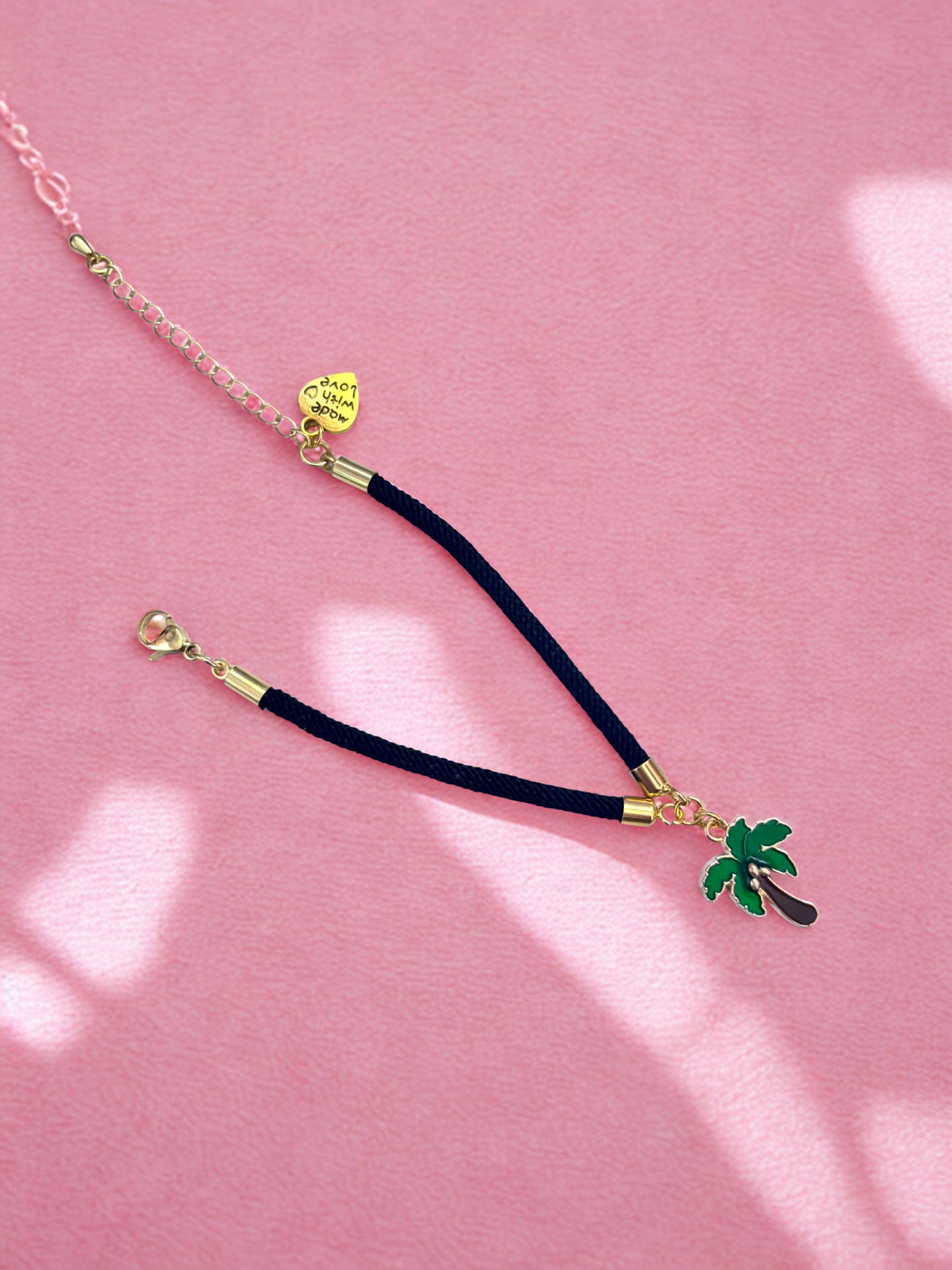 Palm tree charm bracelet against a pink background