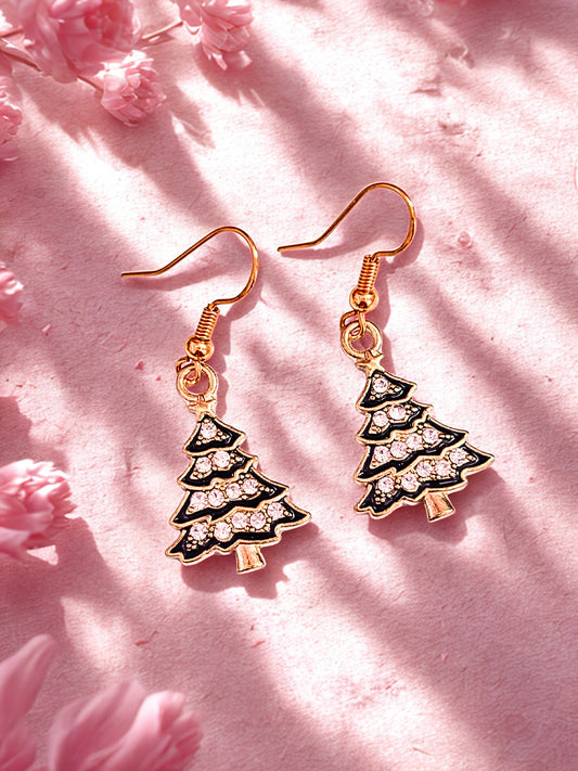 Black & gold Christmas tree earrings with sparkles, laid on a soft pink surface