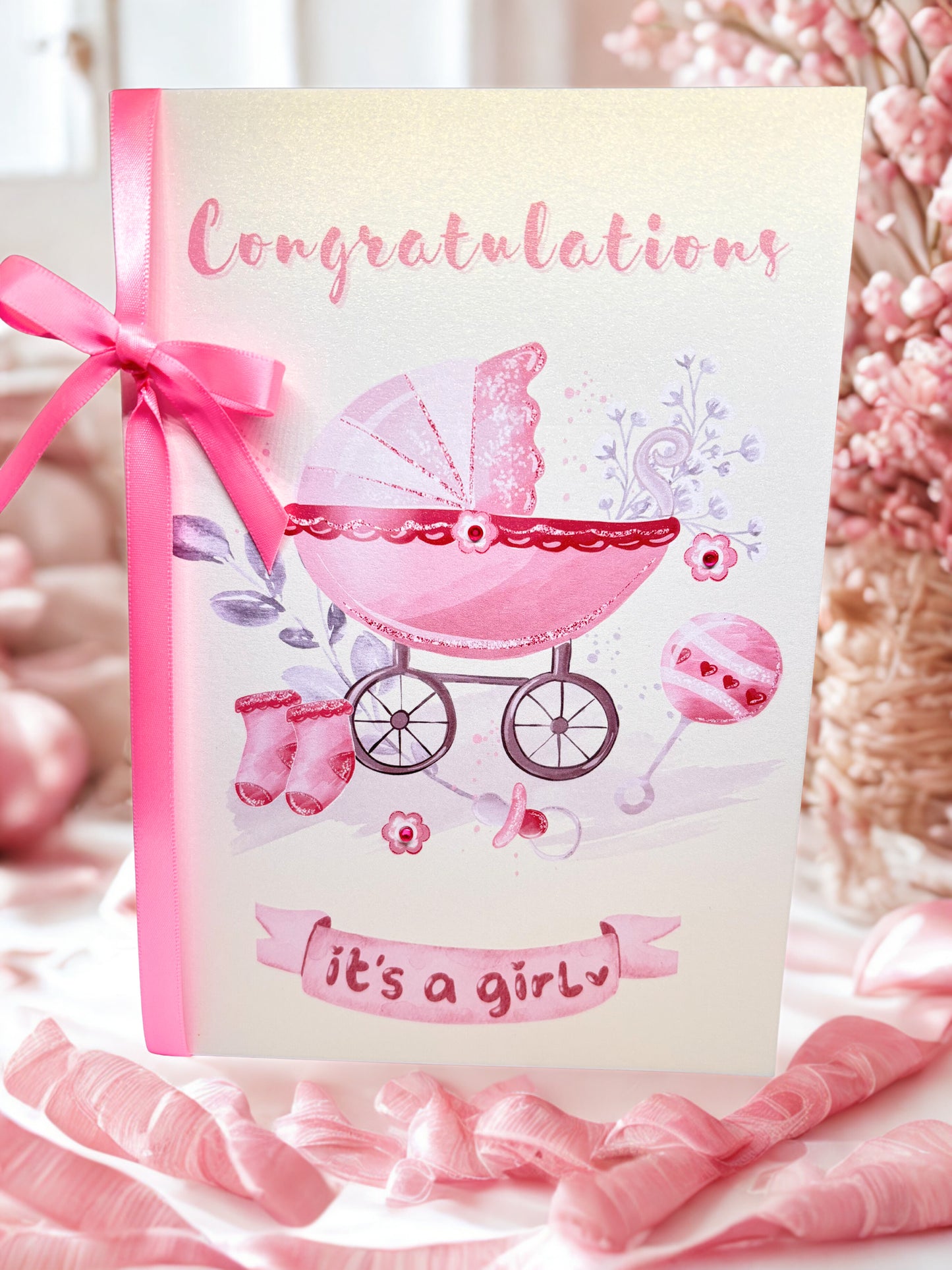 Baby shower card with pink baby carriage and 'Congratulations it's a girl' text, surrounded by pink ribbons and flowers.