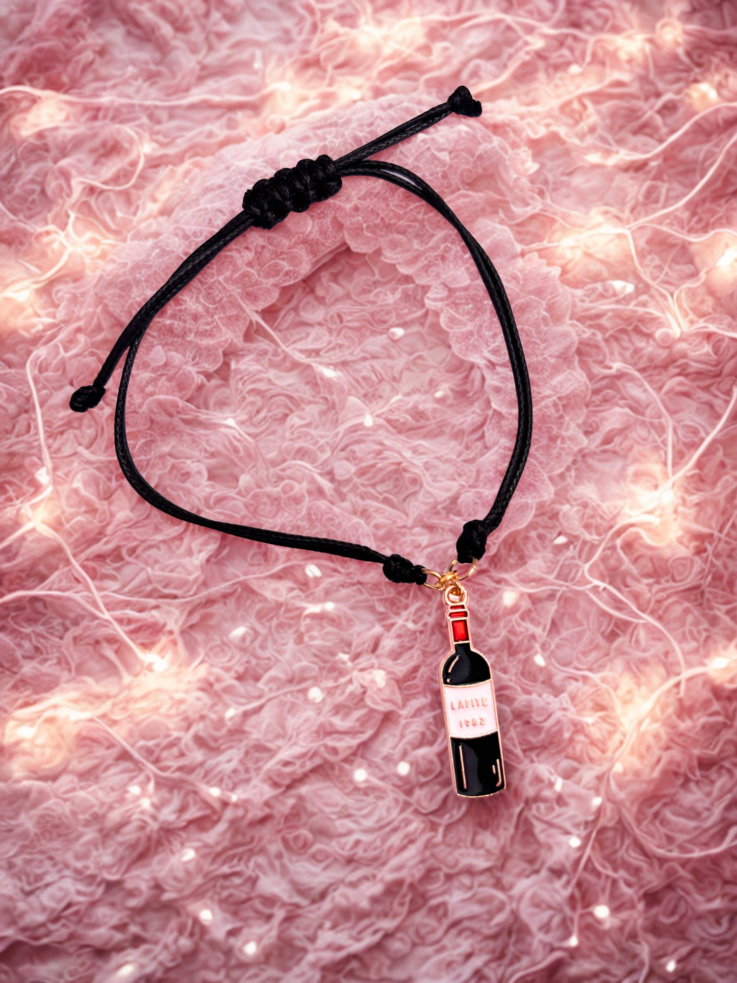Black cord bracelet with a wine bottle charm on a pink marble background