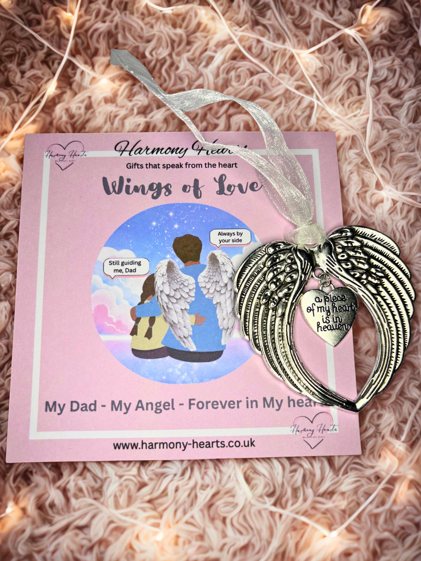Silver angel wing ornament with heart charm on a pink card with 'Harmony Hearts' branding.