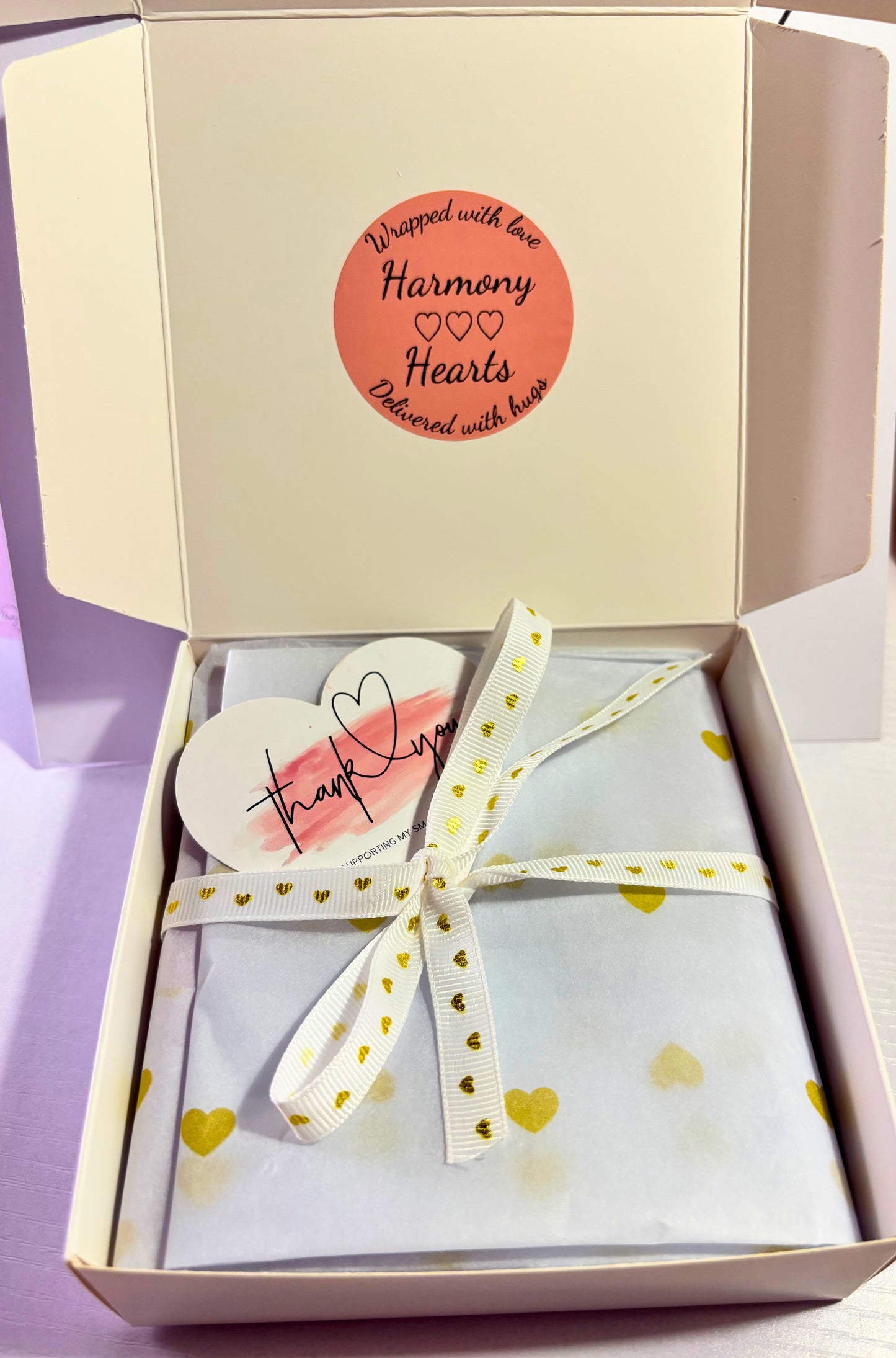 Gift box with a heart-shaped card and bow on a light purple background
