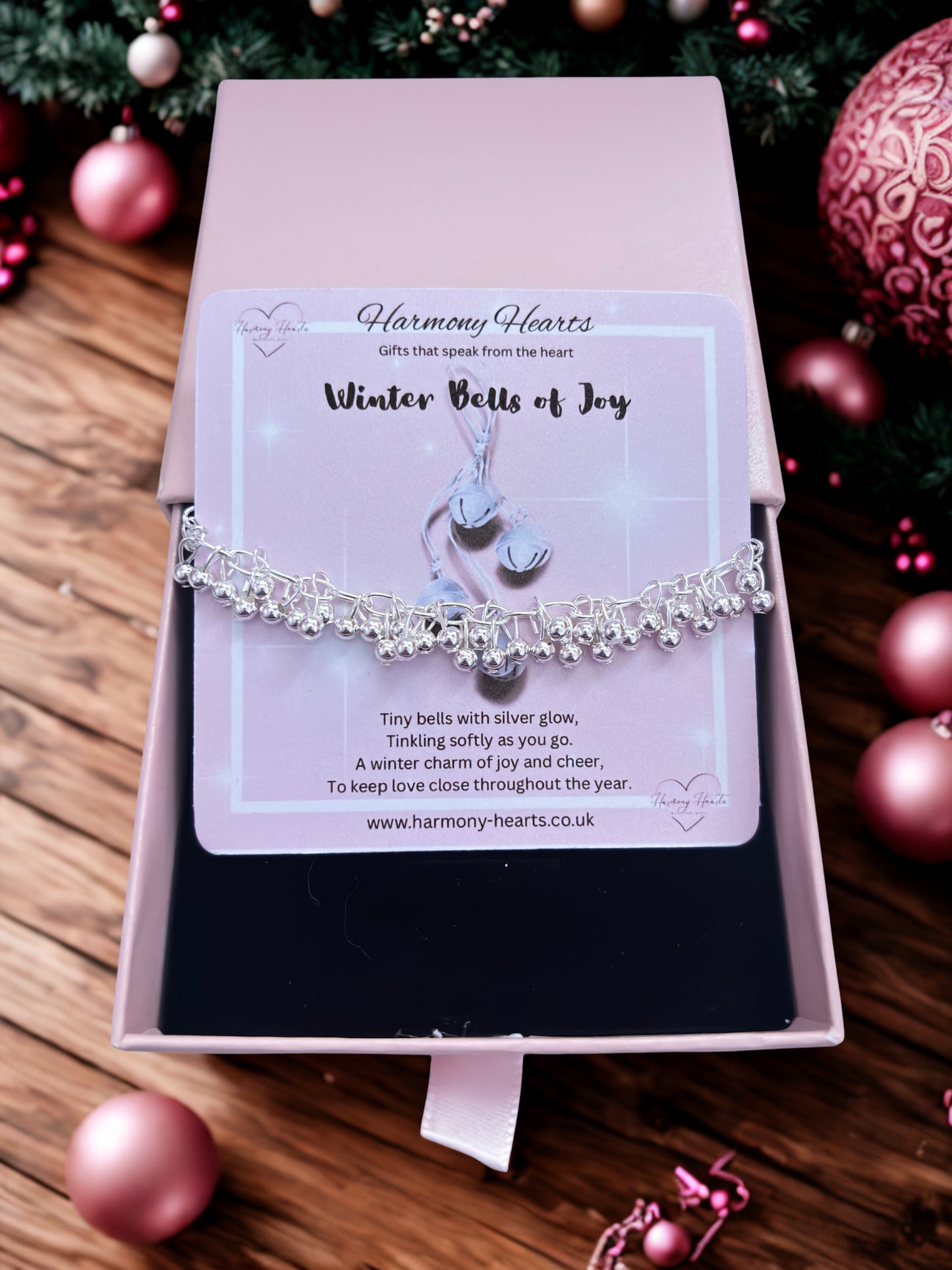 Silver bracelet on a card with 'Harmony Hearts' branding, surrounded by Christmas decorations.