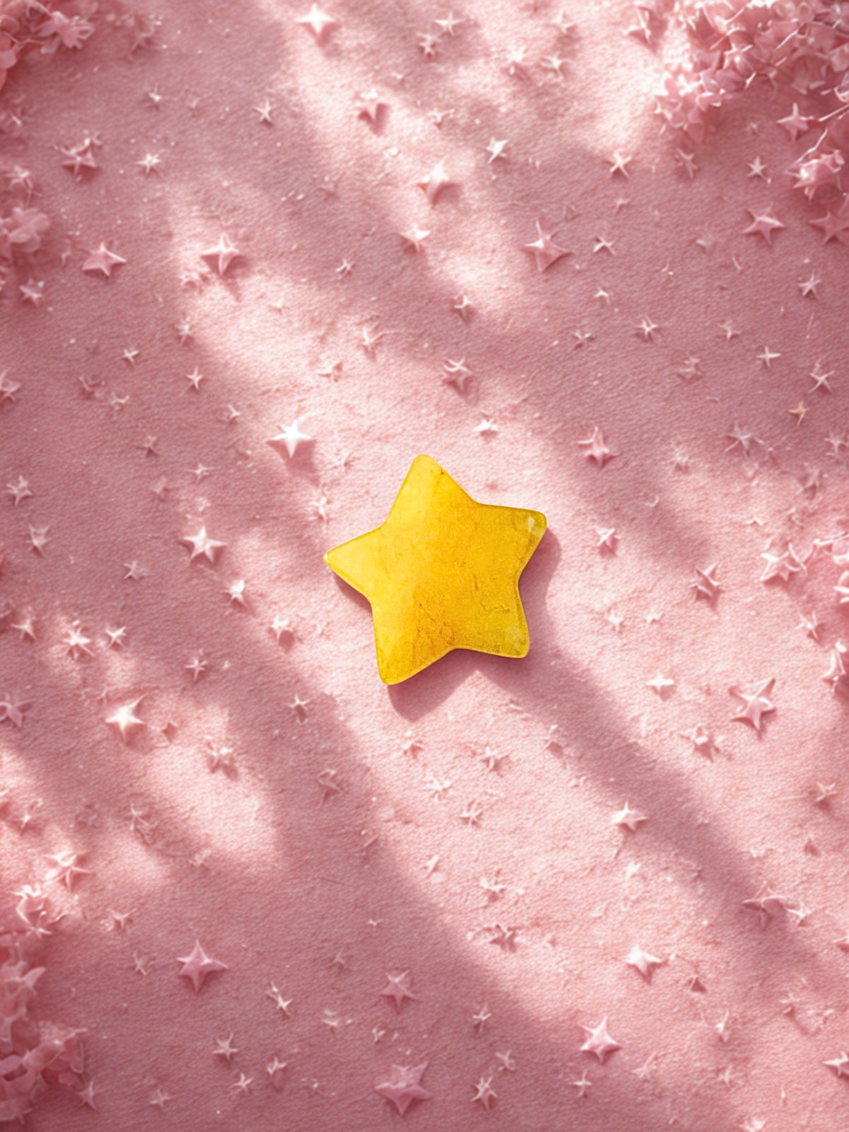 Yellow citrine star on a pink textured background with smaller stars
