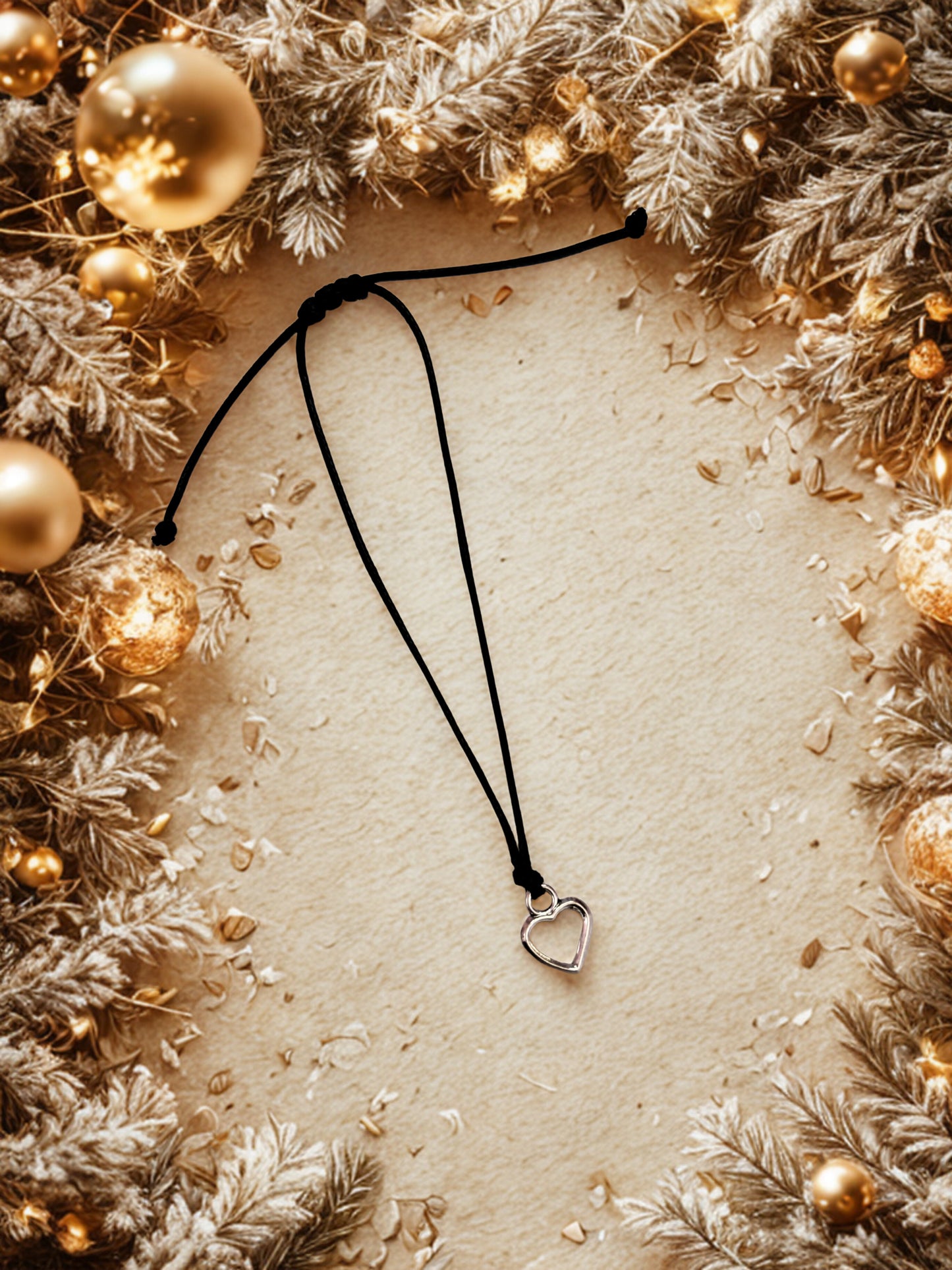 Bracelet with a heart pendant on a beige background surrounded by Christmas decorations.