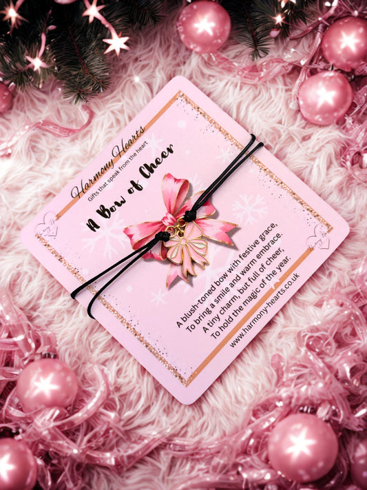 Pink bow of cheer charm bracelet with decorative card on a fluffy white surface with pink ornaments.