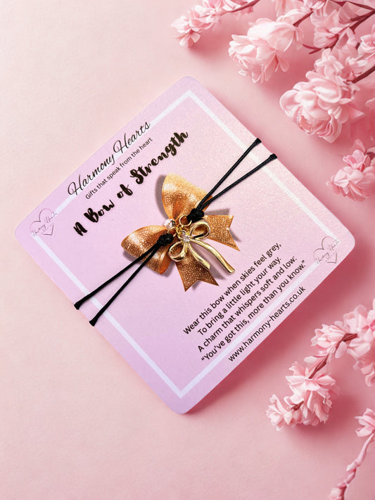 Pink card with a a cord charm bracelet with gold bow on a pink floral background