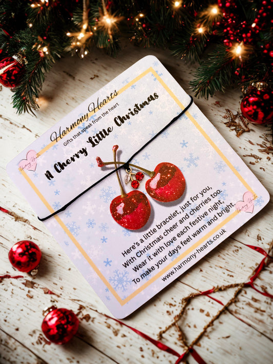 Christmas-themed card with red glittery cherries and festive decorations on a wooden surface.