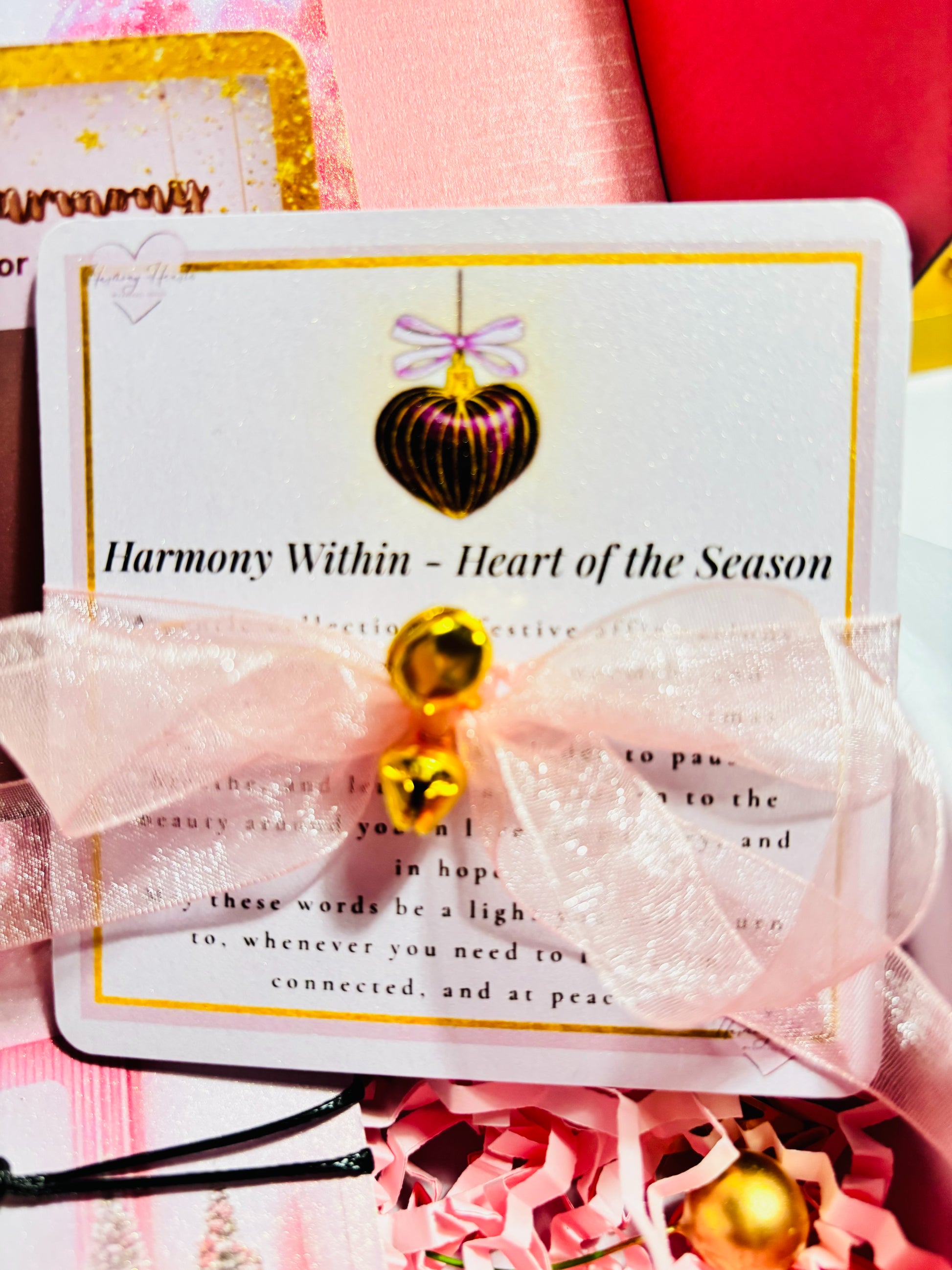 Card with gold ornament and text 'Harmony Within - Heart of the Season' on a pink background