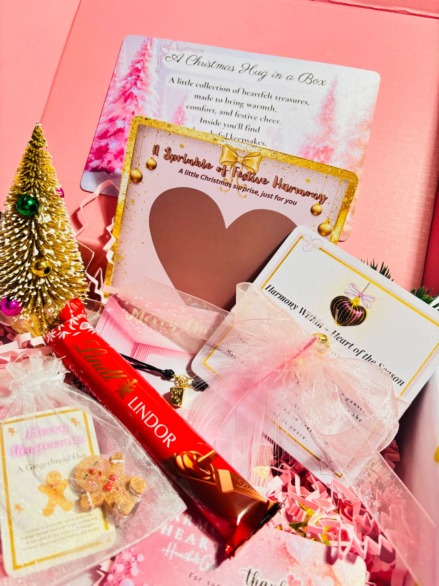 Pink gift box with Lindor chocolate, cards, and decorative items on a pink background